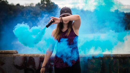 Woman throwing blue smoke in the air